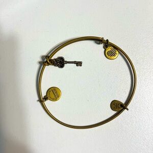 Alex and Ani gold colored key bracelet with topaz colored stone